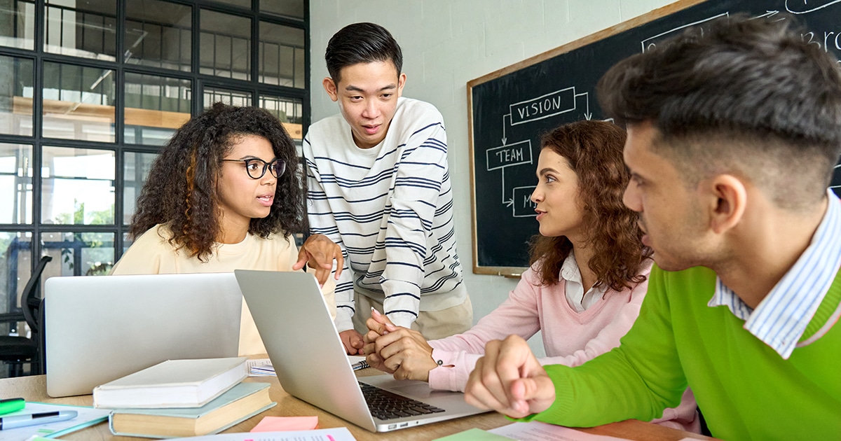 Group of young people working in a shared desk with laptops