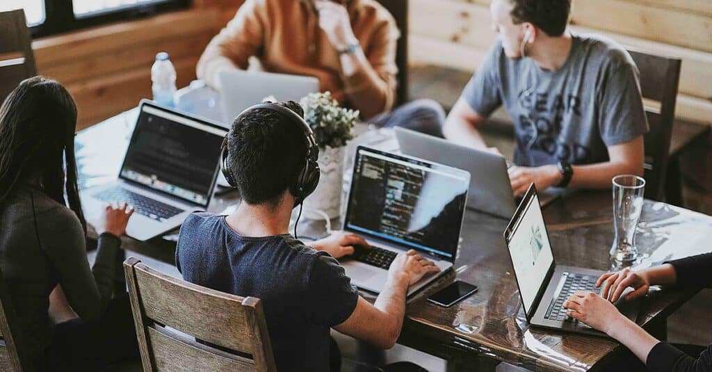 Group of young people working in a shared desk with laptops