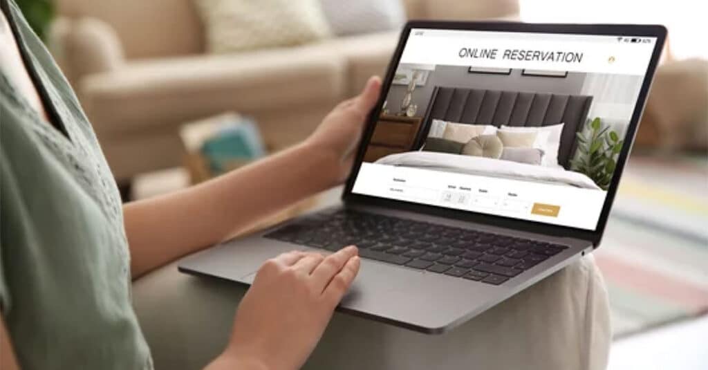 Woman with a laptop browsing in a website for booking in a hotel