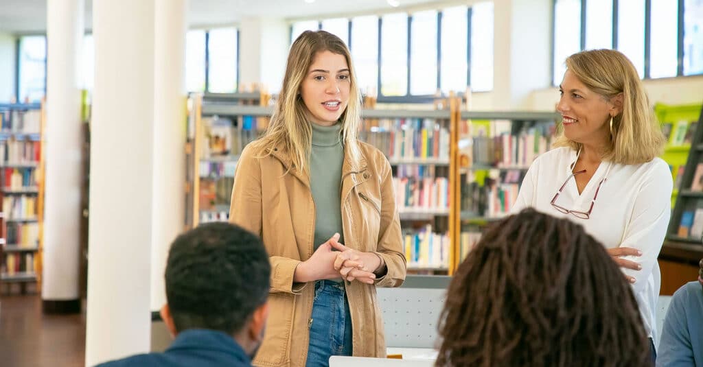 Young woman speaking in a public library to an audience during an event on government digital transformation