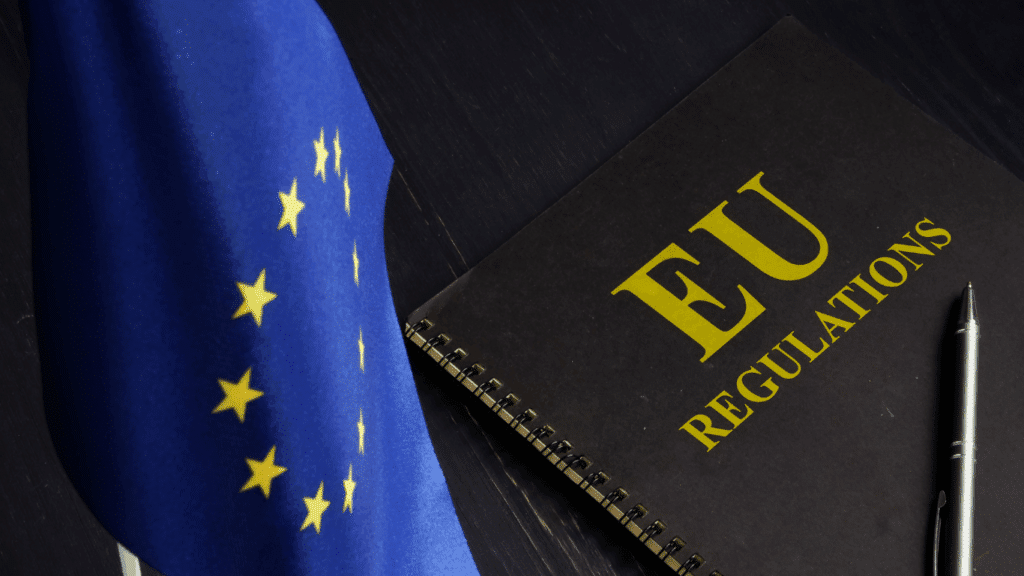 Image of a black notebook with a cover reading "EU regulations" next to the blue European flag with stars