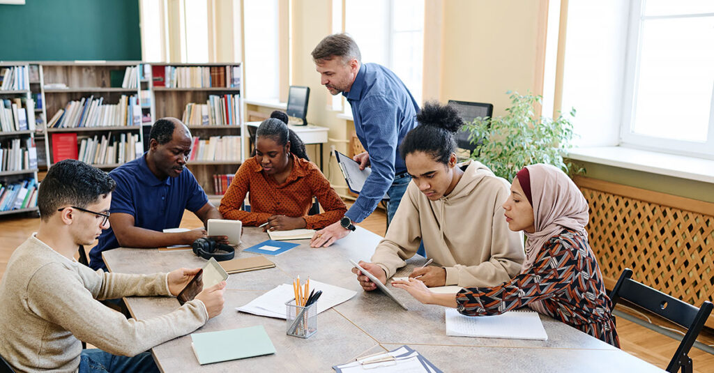 Students working together in a modern library, collaborating with digital devices supported by education IT solutions.