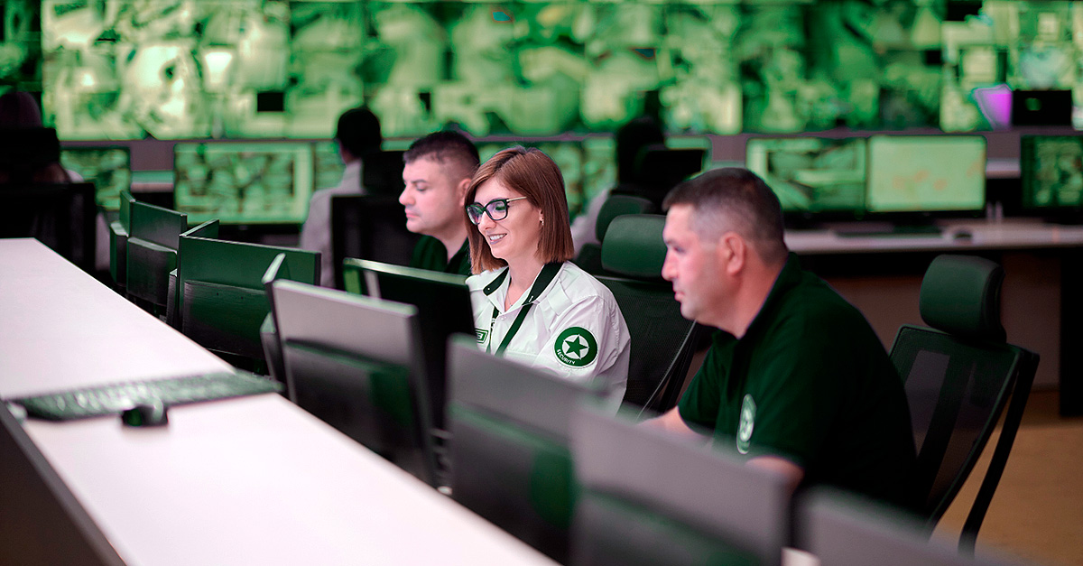 A team of cybersecurity professionals monitors multiple screens in a modern security operations center, analyzing data to detect and prevent IoT security risks.