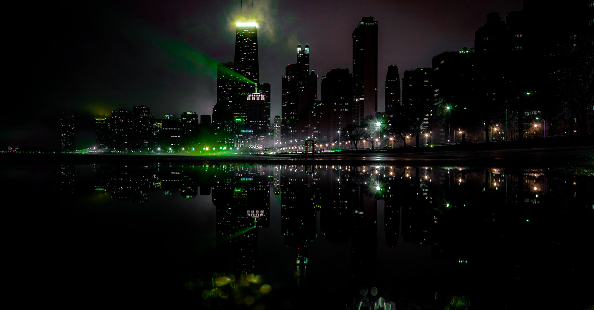 A city skyline at night, illuminated in green for a specific event or cause.